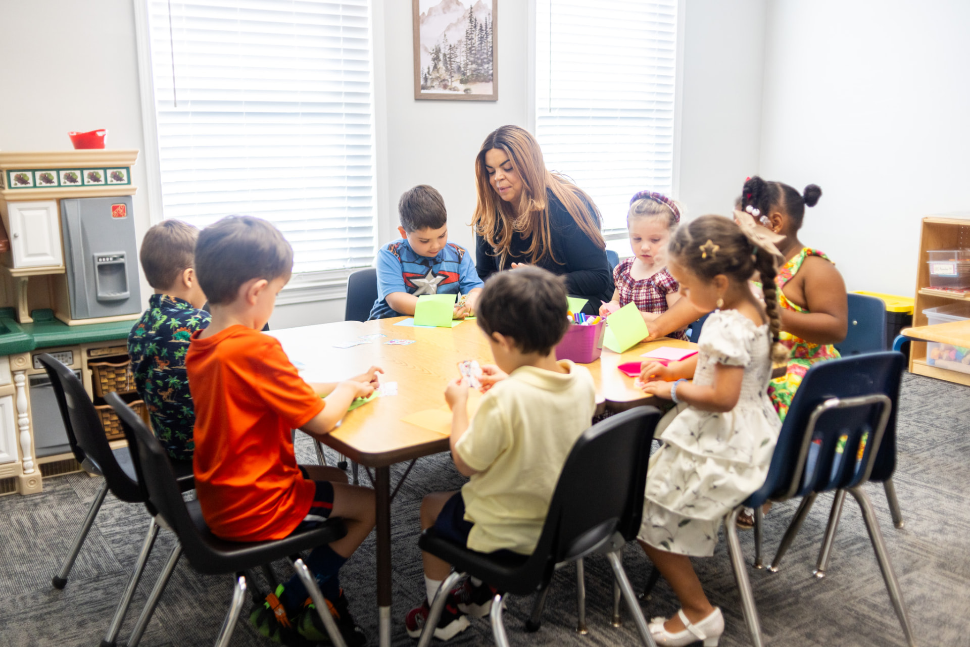 Preschool children making crafts at a table with their teacher