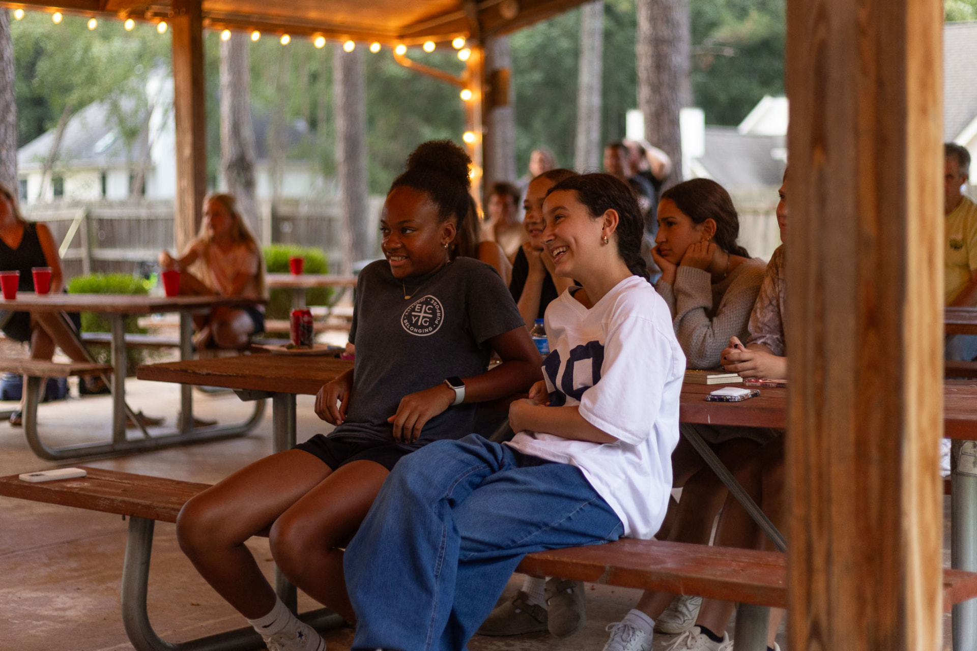 Students laughing together at a picnic table during a student ministry night